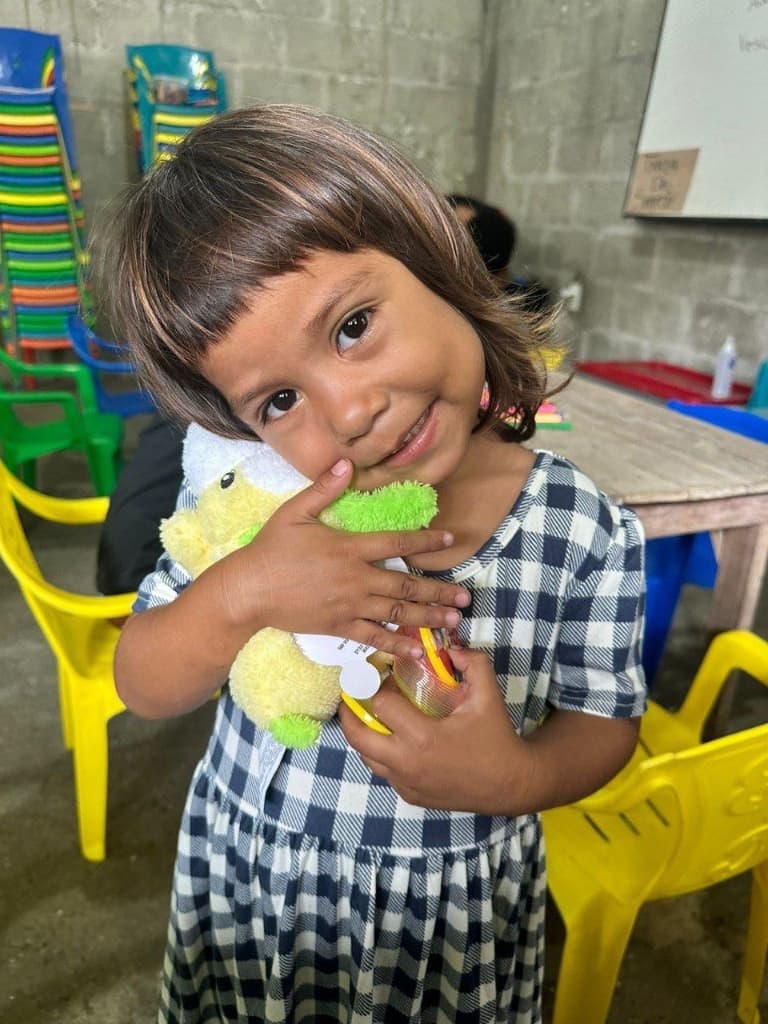 Niña abrazando un peluche recibido en una brigada